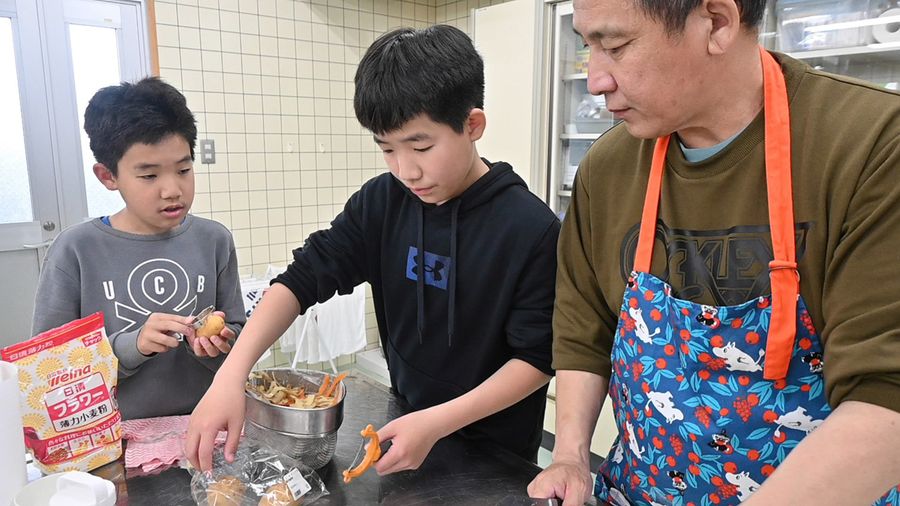 息子たちに手ほどきするバスカさん＝右