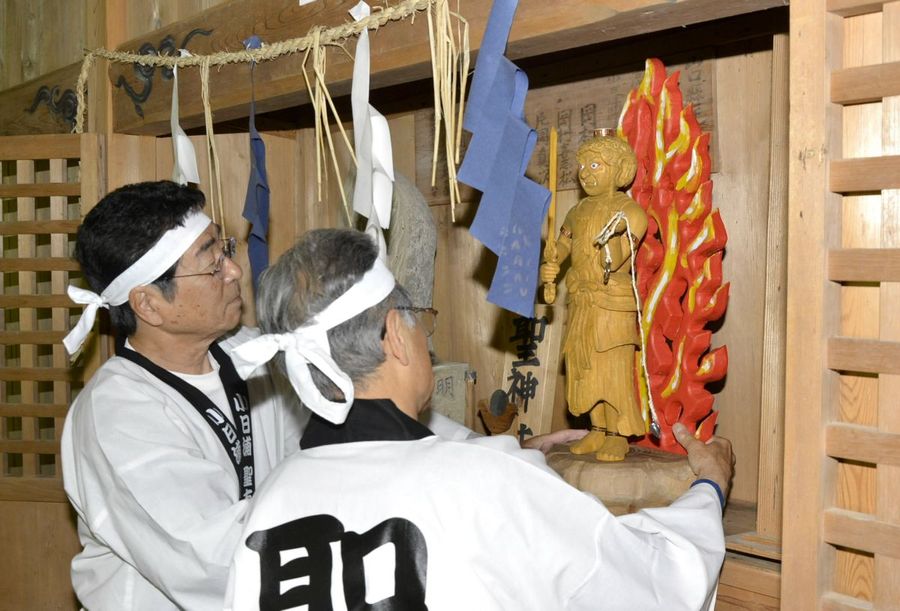 不動明王の木像を奉納する「小日浦聖友会」のメンバー。左は元々あった石像（越知町南ノ川の聖神社）