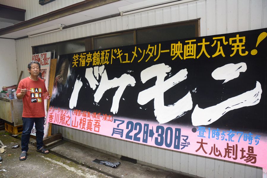 「バケモン」の看板を描き上げた小松秀吉さん(安田町の大心劇場)