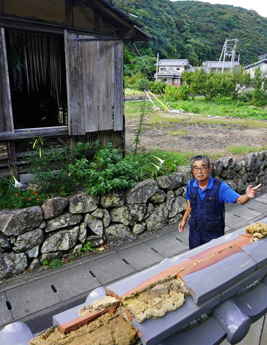 「いつ人が流されてもおかしくなかった」と豪雨を振り返る岡林秀明さん。救出のためはしごを掛けた自宅の塀=手前=は壊れた当時のままだ(大月町周防形)