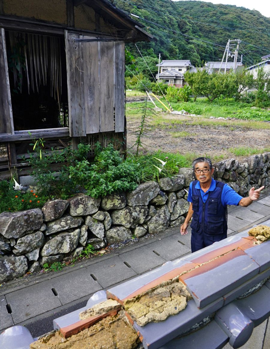 「いつ人が流されてもおかしくなかった」と豪雨を振り返る岡林秀明さん。救出のためはしごを掛けた自宅の塀＝手前＝は壊れた当時のままだ（大月町周防形）