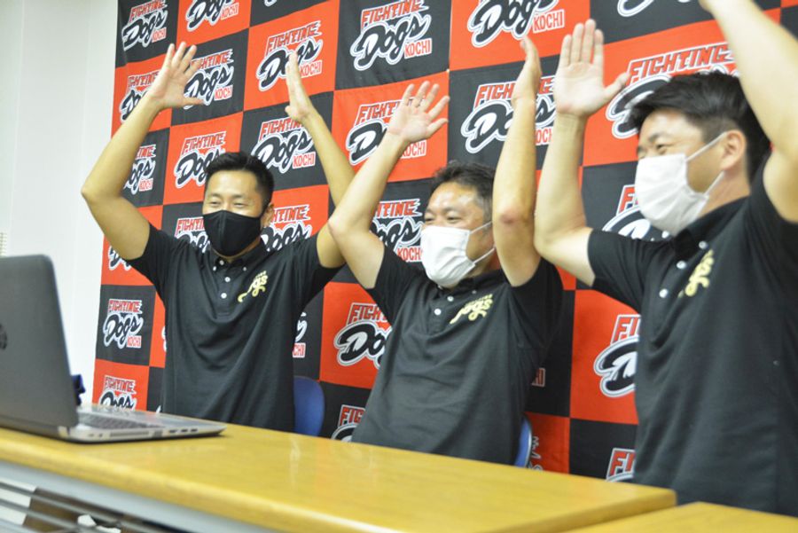 優勝の胴上げに合わせ、祝福する武政重和社長=中央=ら高知FDの球団関係者(高知市大谷公園町)