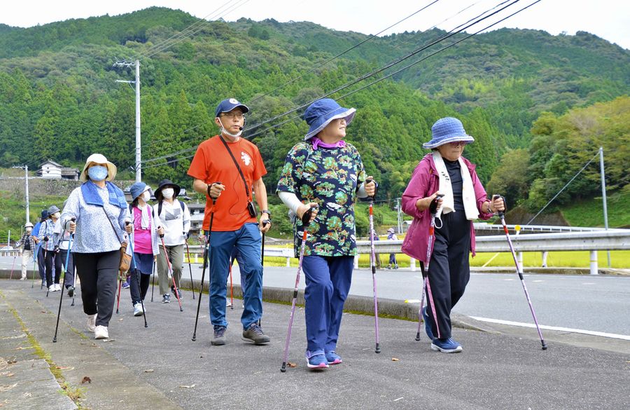 秋の里山の景色を楽しみながらポールをついて歩く参加者