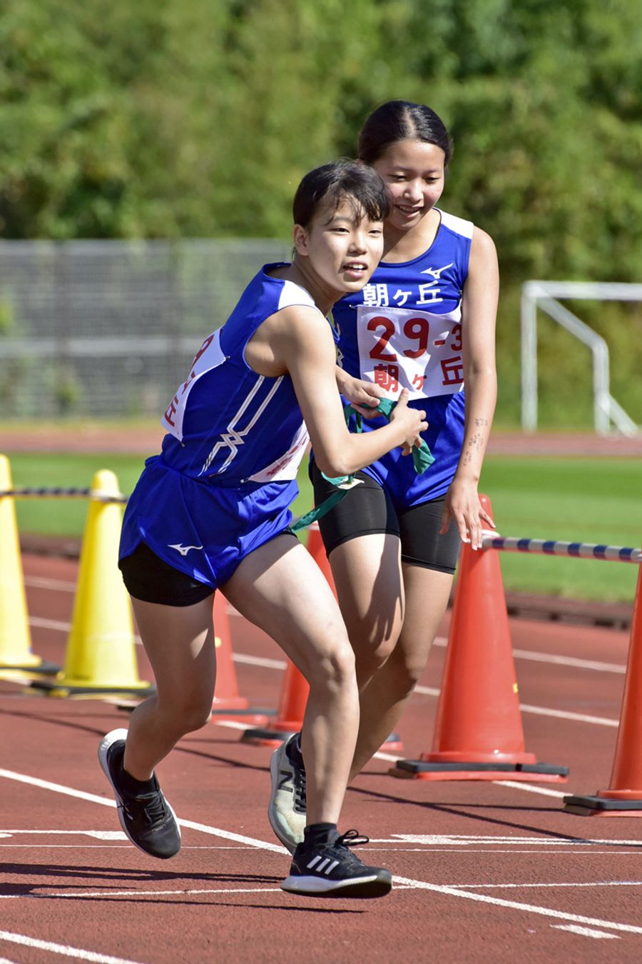 朝ケ丘Aの3区茂木皐月=右=がリードを保って、4区弘瀬英乃玲にたすきをつなぐ(春野運動公園)