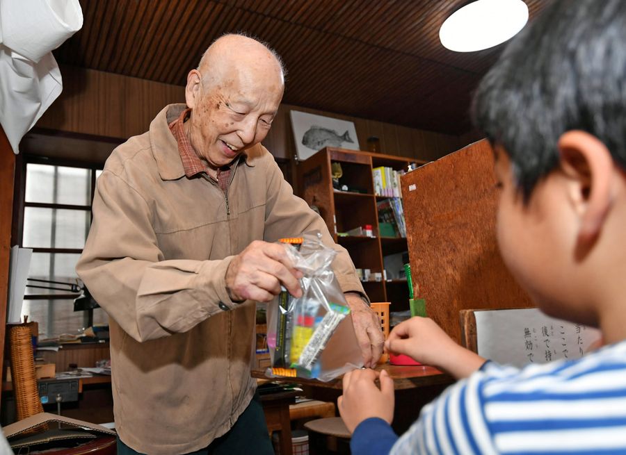 「はい、どうぞ」。お菓子を入れた袋を子どもに手渡す藤田晋一郎さん(写真はいずれも高知市新屋敷1丁目=山下正晃撮影)