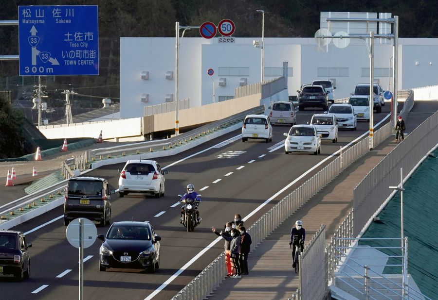 一般通行が始まった高知西バイパスの鎌田インターチェンジ付近。通り初めする車に手を振る人の姿も(いの町鎌田=反田浩昭撮影)
