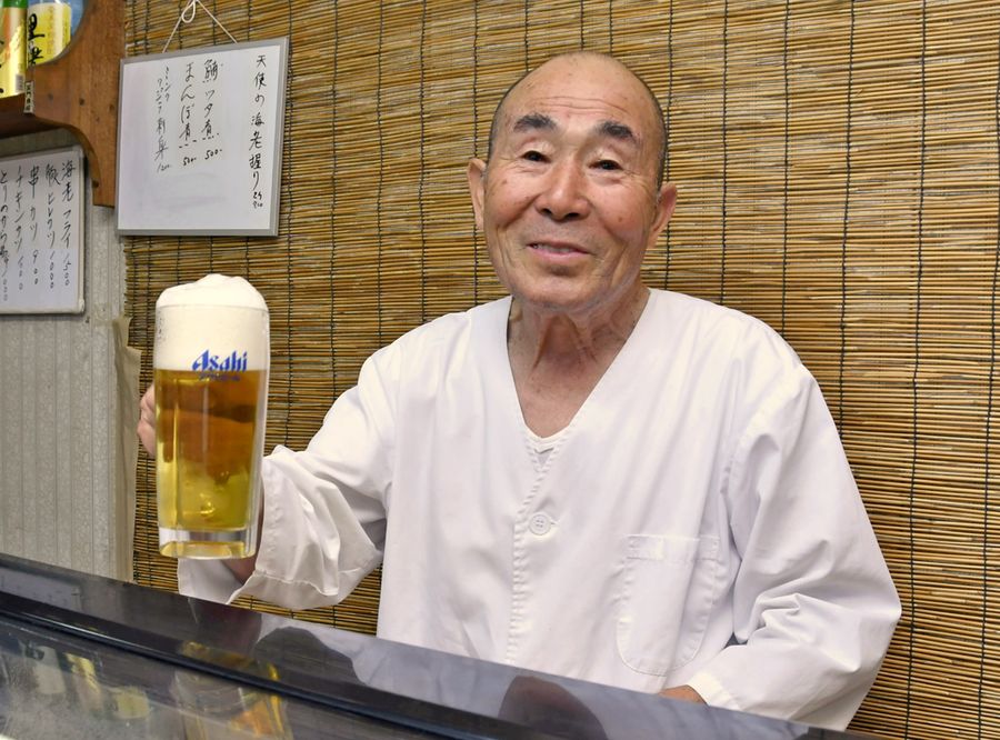 店主の久保幸雄さん。ジョッキの上まで泡が盛られたビール