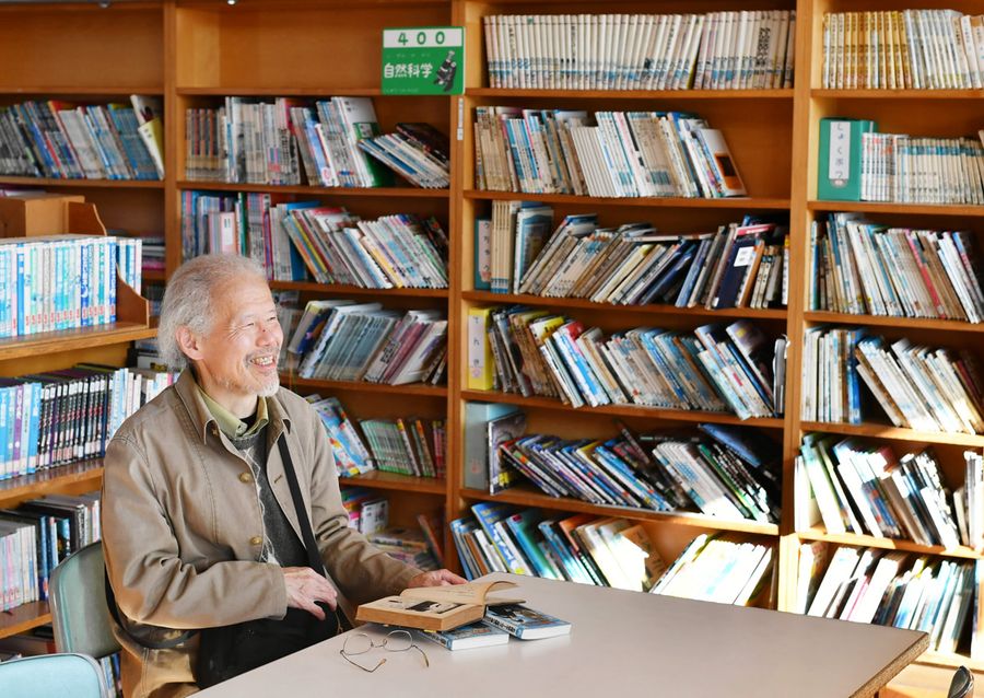 懐かしい図書室に座る西澤保彦さん。ここで初めて読んだミステリーの結末を知らない（安芸第一小＝山下正晃撮影）