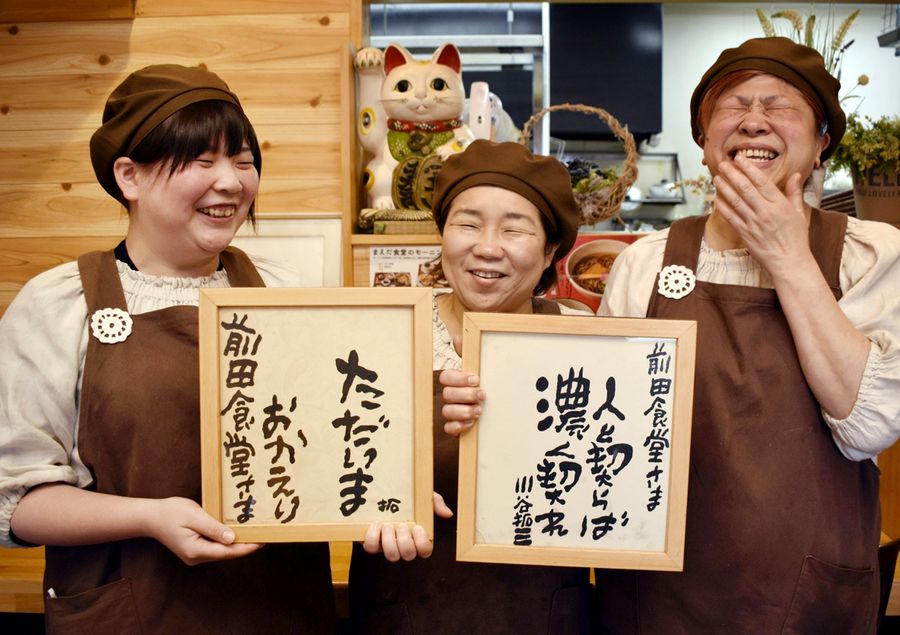 故川谷拓三さんの色紙と店主の斉藤真紀さん=中央=ら