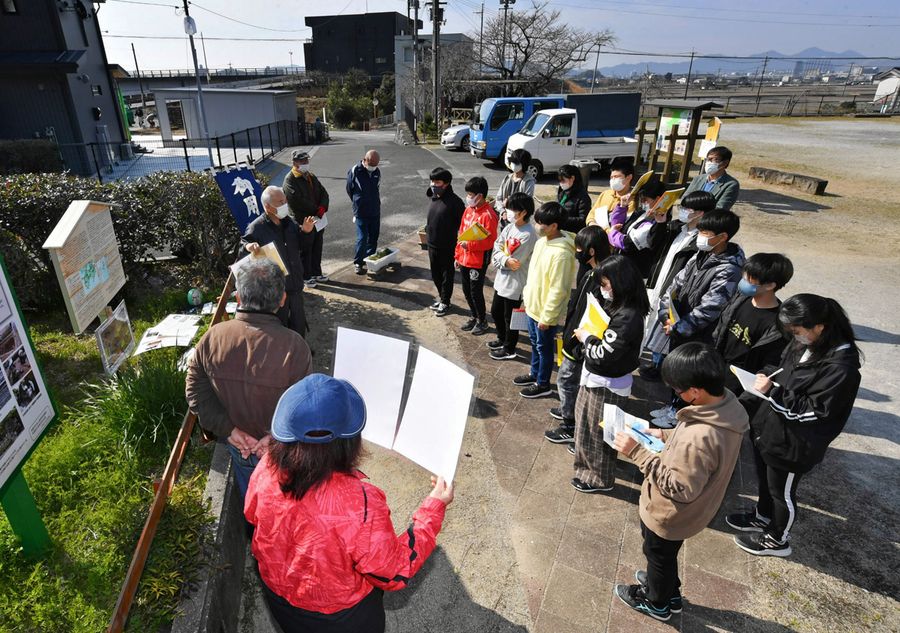 伊能測量の解説に耳を傾ける児童たち。昨年末には、歴史を解説する看板も新設された（高知市の布師田ふれあいセンター前＝山下正晃撮影）