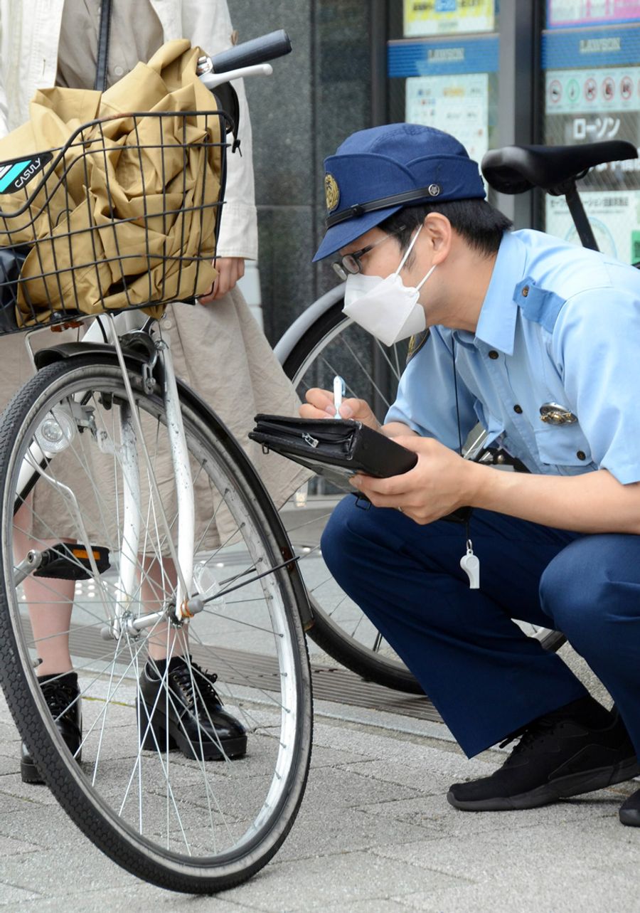 自転車の防犯登録などを確認しながら街頭指導する警察官（高知市はりまや町１丁目）