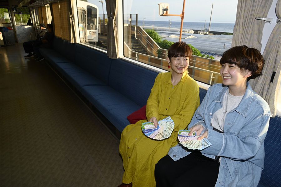 「いろいろ行ったね」。ごめん・なはり線の車内で談笑する西内博子さん=左=と萌々子さん。手元には、これまで使った1日乗車券がどっさり(安芸市下山)
