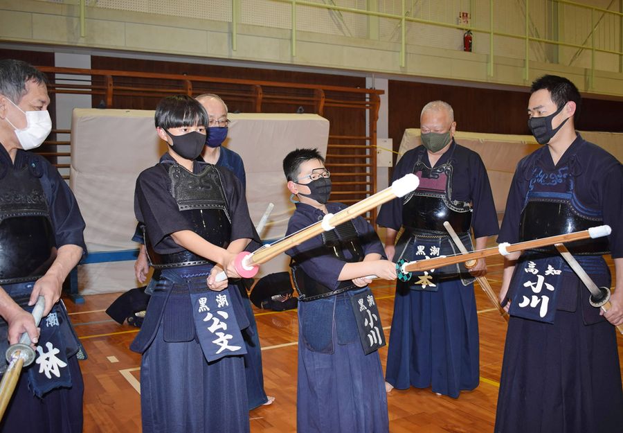 大人４人に囲まれ構え姿勢の指導を受ける部員２人（写真はいずれも高知市百石町２丁目の潮江小学校体育館）