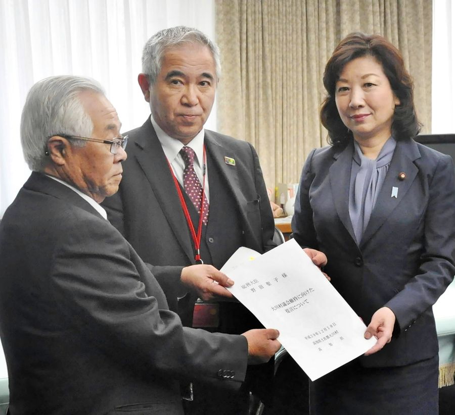 議会の維持に向け、当時の野田聖子総務相(右)に兼業規制緩和などの提言書を手渡す和田知士村長(中)ら=2017年12月、総務省