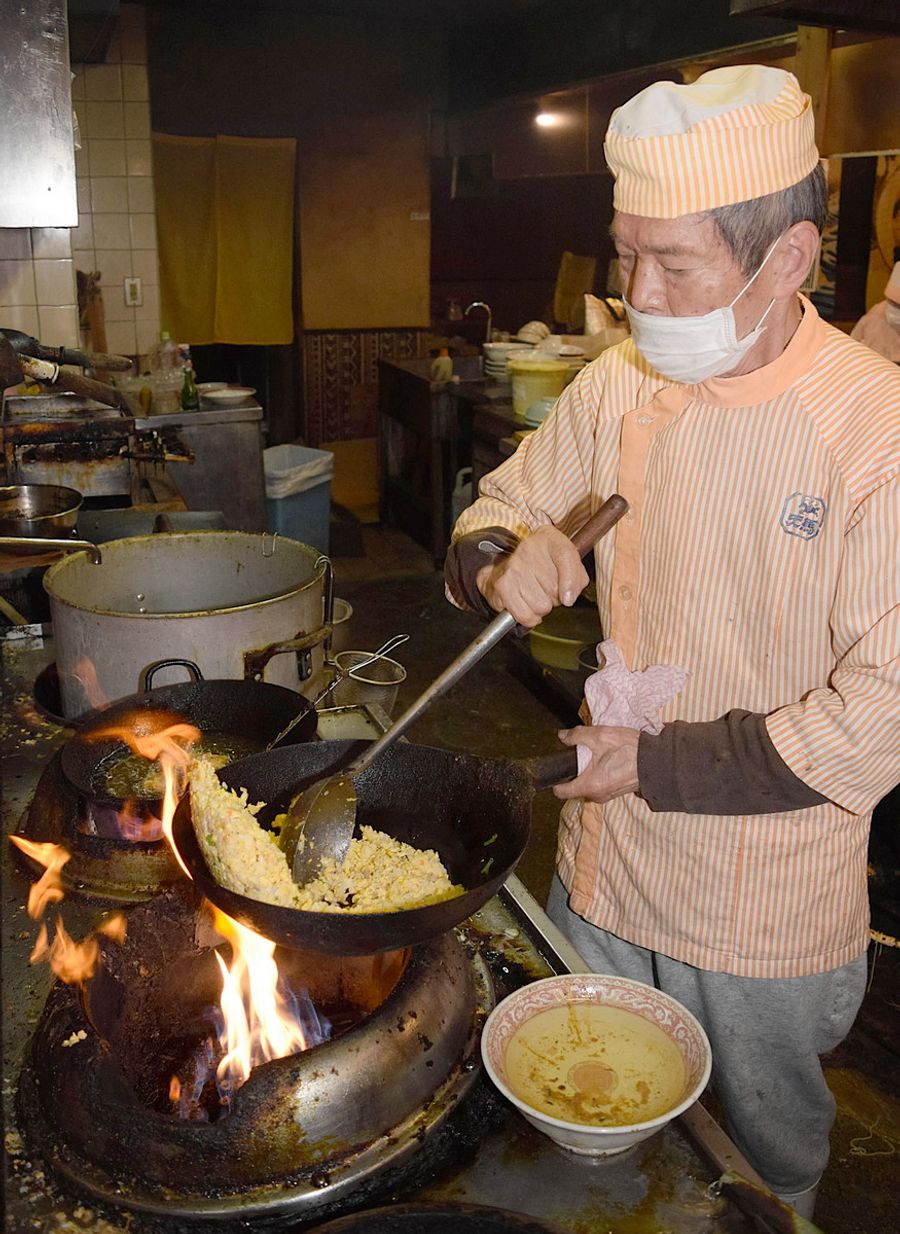 鉄鍋でチャーハンをあおる吉田誠児さん。客は「あの味は他じゃ出せん」