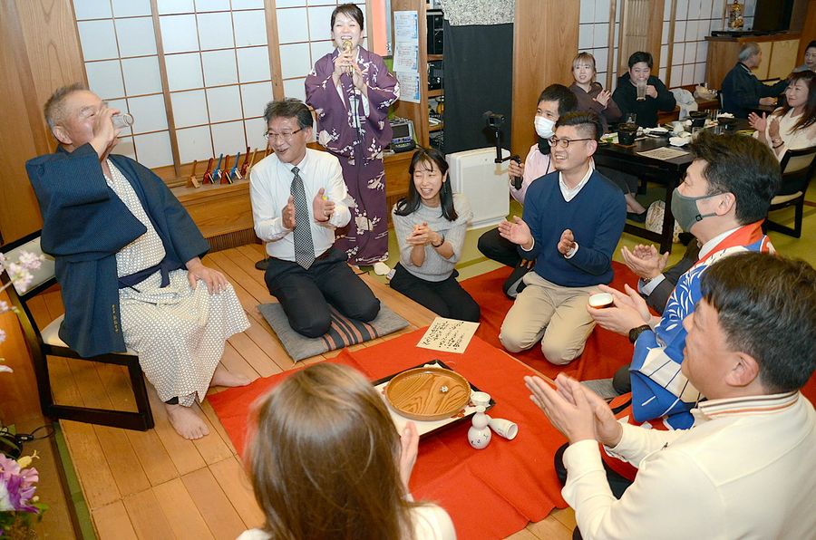 「土佐の『おきゃく』」でお座敷遊びを体験する人たち。べく杯についだ酒をグラスに移して飲む工夫も（８日、高知市追手筋１丁目）