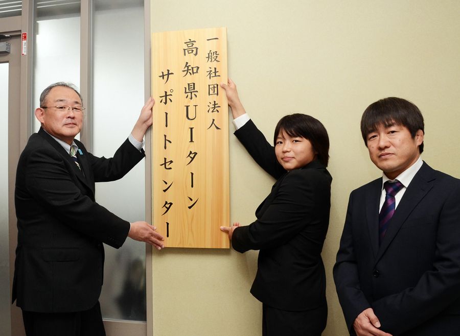 「県ＵＩターンサポートセンター」の看板を付け替える桜井つぐみさん＝中央＝と優史さん＝右＝親子（高知市本町４丁目）