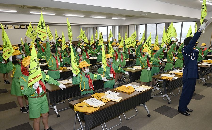 街頭指導で使う旗の振り方を教わる新団員たち（南国市大そね乙の南国署）