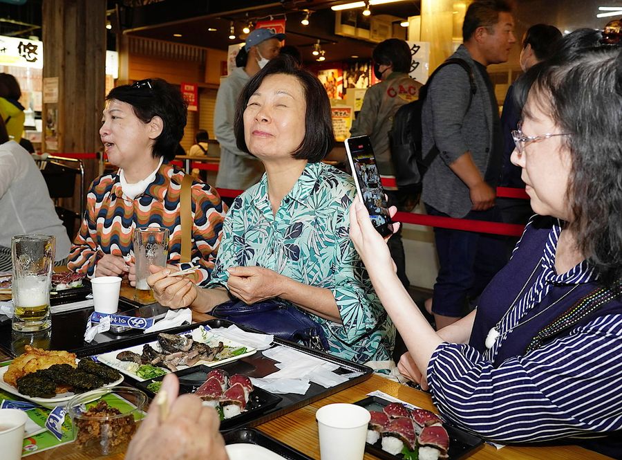 ひろめ市場で夕食を取る台湾のツアー客。わら焼きカツオを食べたら、この表情（１２日、高知市帯屋町２丁目）