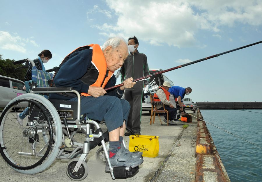 身を乗り出して釣りに集中する施設利用者。職員が付き添い安全を確保している(写真はいずれも香南市夜須町の手結港)