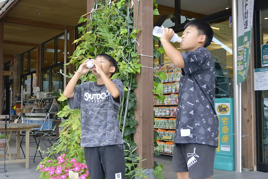 「あつー」。ジュースを飲み干し水分を補給する男児（四万十市西土佐江川崎の道の駅「よって西土佐」）