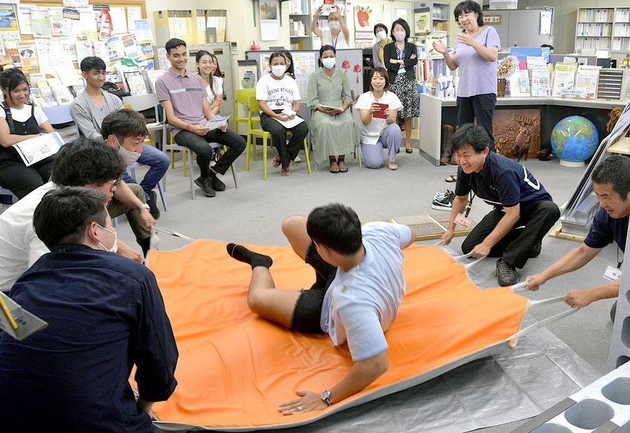 地震の疑似体験をする県内在住の外国人ら（高知市本町４丁目）