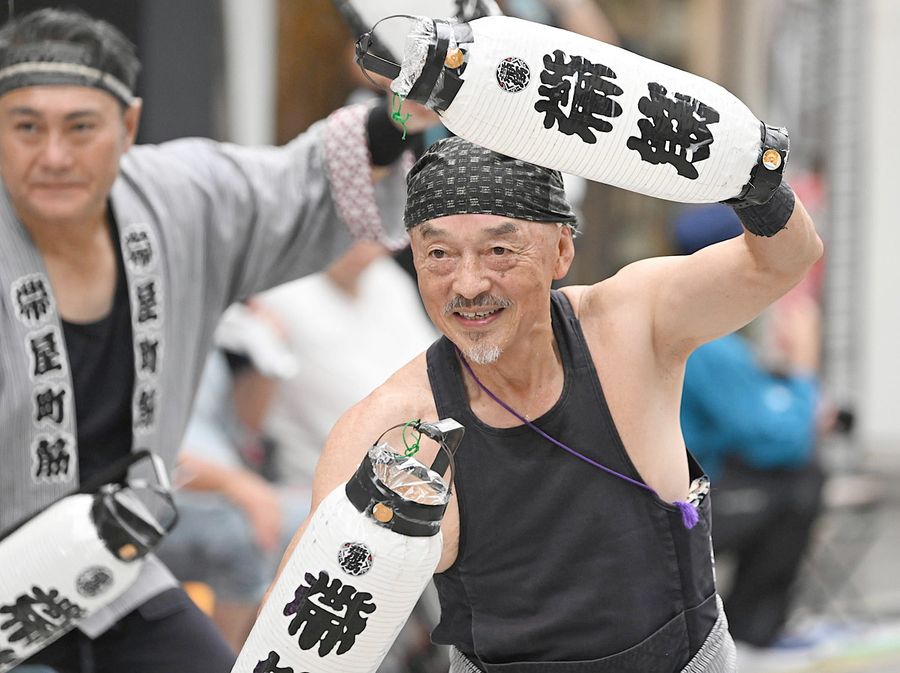 にかっと笑い、ちょうちんを振る長山益男さん（帯屋町演舞場＝佐藤邦昭撮影）