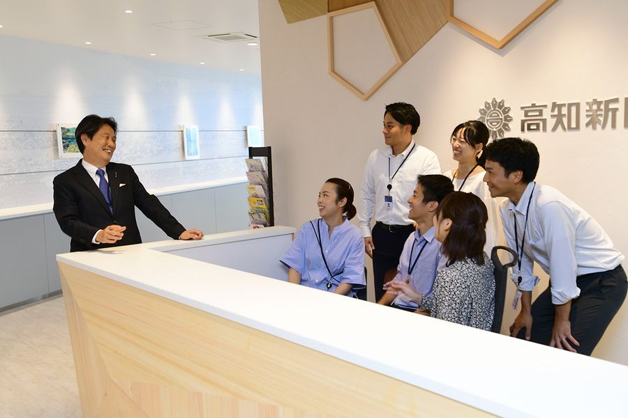 新社屋８階のエントランスで談笑する、中平雅彦社長＝左＝と若手社員たち（高知市本町４丁目の高知電気ビル）