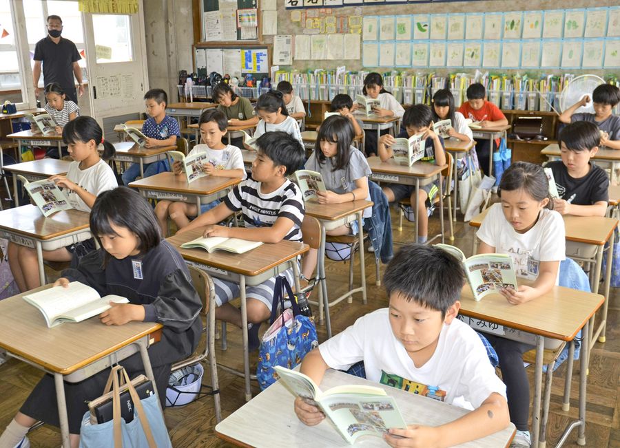 贈られた作品集を読む児童(南国市の大篠小)