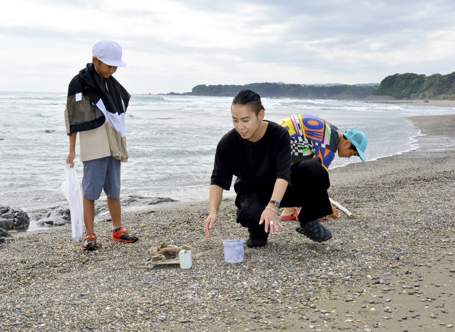砂浜で児童らと小物作りの素材を集める小西翔さん(黒潮町田野浦)