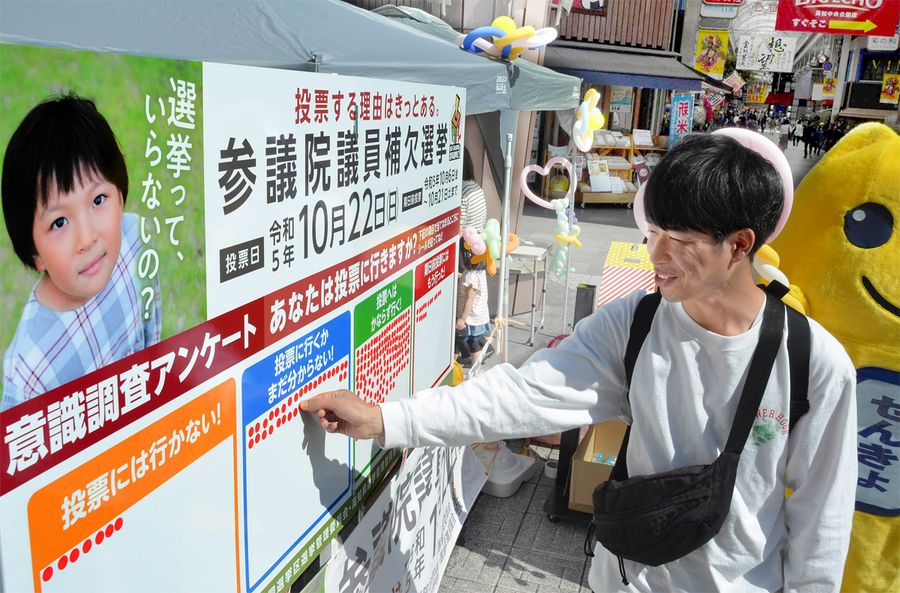 シールを張って投票に行くかどうか答える若者（高知市の中央公園）