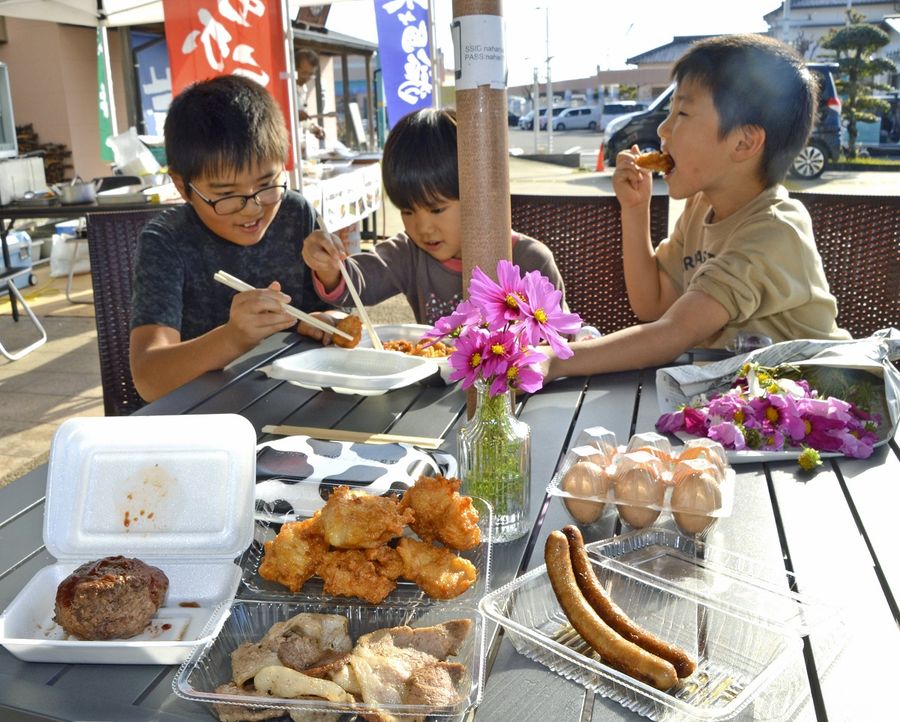 地元産の肉で作った料理を頬張る子どもたち(奈半利町の奈半利駅)
