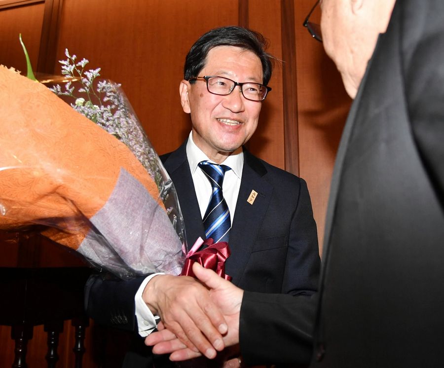 花束を手に、笑顔で支持者と握手を交わす浜田さん（２６日午後８時半ごろ、高知市鷹匠町１丁目）