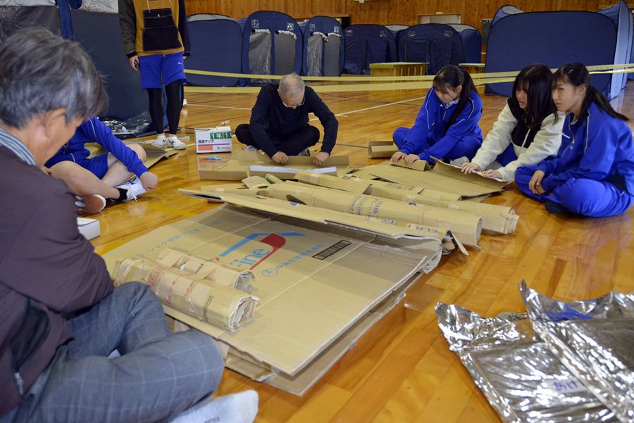 段ボールを丸めてマットレスの代用にしたベッドを作る高校生ら（黒潮町の大方高校）
