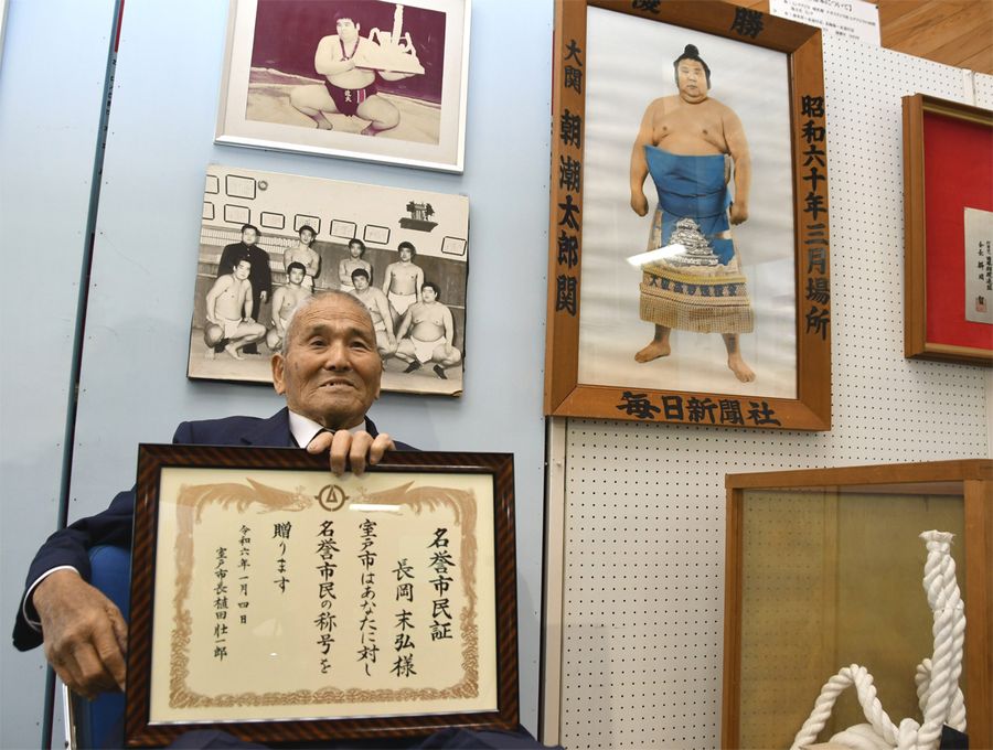 長岡末弘さんの写真の前で名誉市民証を手に在りし日を懐かしむ父、友久さん（室戸市役所）