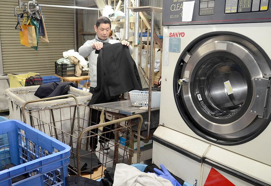 衣類を仕分けるミッキークリーニングの住本和之社長。原油高騰の影響も受け、返済計画を見直した(高知市横浜西町)