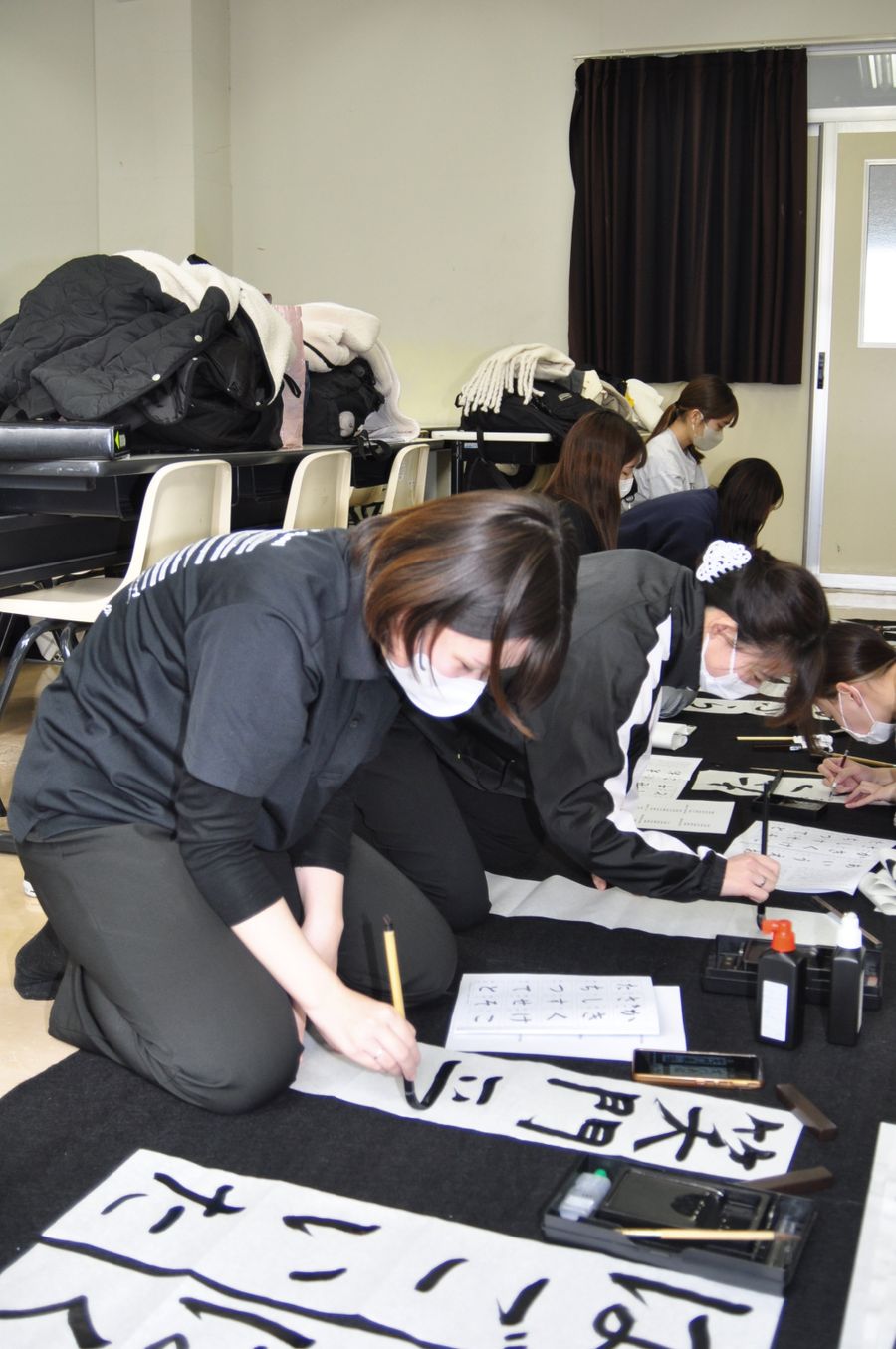 真剣な表情で筆を運ぶ学生たち（高知市の高知学園短期大学）