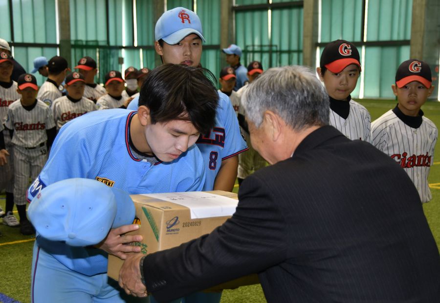 関係者から記念品を受け取る韓国の球児（室戸市の県立室戸広域公園屋内運動場）