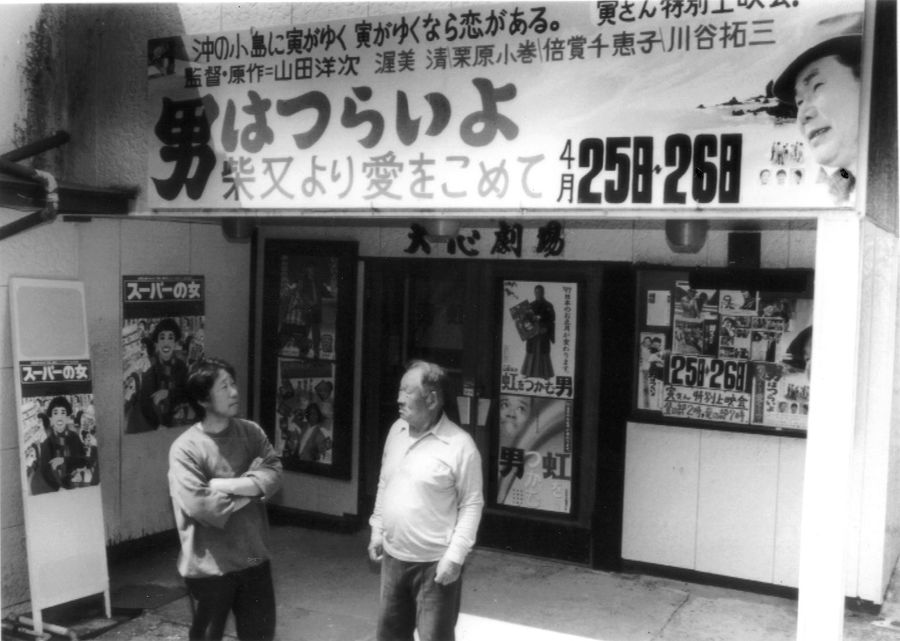 大心劇場の入り口に立つ若き日の小松さん（左）と父の博行さん（１９９７年ごろ）