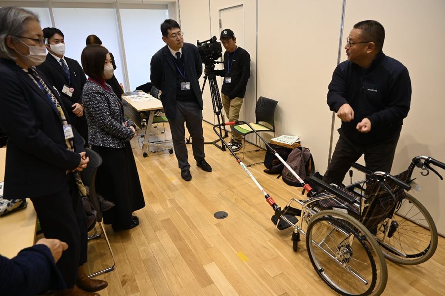 車いすを人力車のように引っ張る器具を説明する渕山知弘さん＝右（高知市追手筋２丁目のオーテピア）