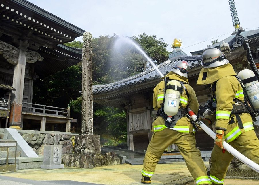 金剛福寺の本堂付近に向けて放水する消防隊員(土佐清水市足摺岬)