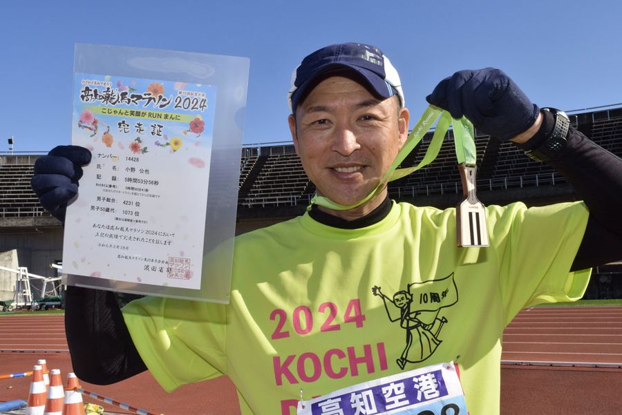 完走メダルと完走証を見せる小野さん（高知市の春野陸上競技場）