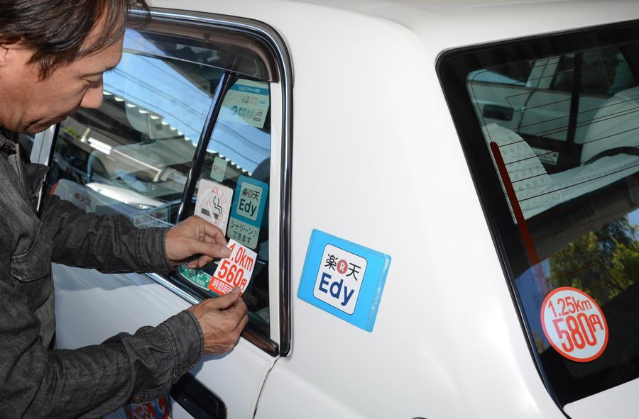 値上げ前日の１８日、車体の運賃表示を張り変えるタクシー会社社員（高知市塩屋崎町２丁目）