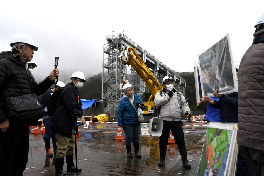 改修工事が進む早明浦ダム堤体の上で工事の説明に耳を傾けるダム愛好家ら（土佐町）