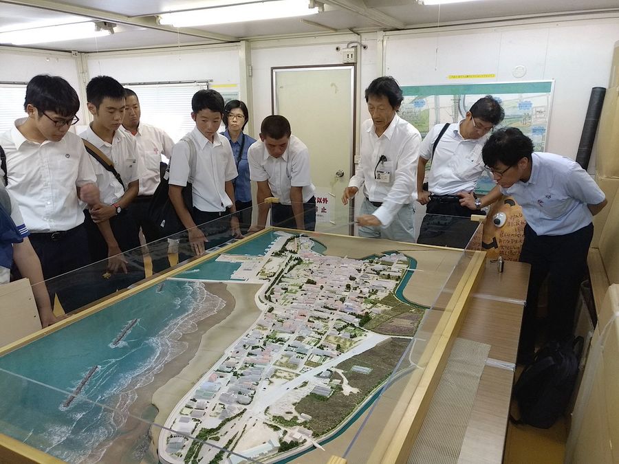 高校生に震災前の街並みを紹介する吉本さん＝右から３人目（２０１８年８月、新地町役場＝吉本さん提供）