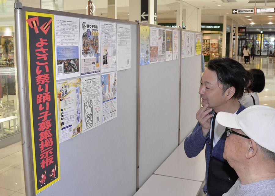 よさこい鳴子踊りの募集掲示板に見入る買い物客ら（高知市秦南町１丁目のイオンモール高知）