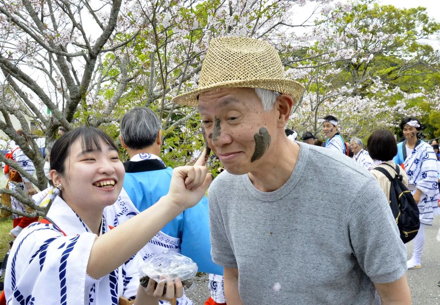 男性の顔にペタペタと泥を塗る女性ら。あちこちで笑い声が上がった（高知市長浜の若宮八幡宮）