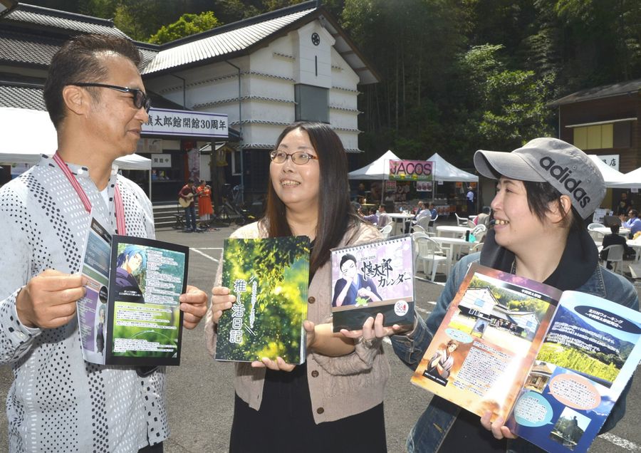 中岡慎太郎のファンクラブ設立に合わせ、関連グッズを配布する松本真由美さん=中央=ら(北川村の中岡慎太郎館)