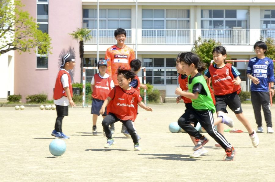 選手にアドバイスをもらいながら、一生懸命ボールを追いかける児童ら(奈半利町乙の奈半利小学校)