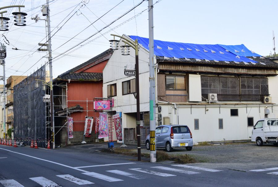 屋根にブルーシートが張られ、修繕に向け足場が組まれるなど復旧の進む宿毛市の市街地（同市中央６丁目）